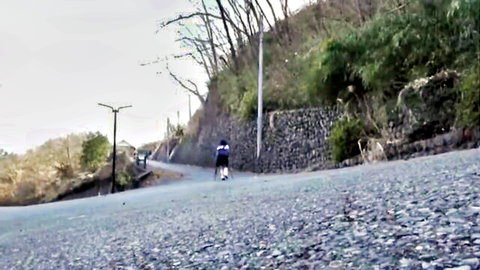 Woman in helmet riding scooter on rural hillside road in JAV outdoor scene