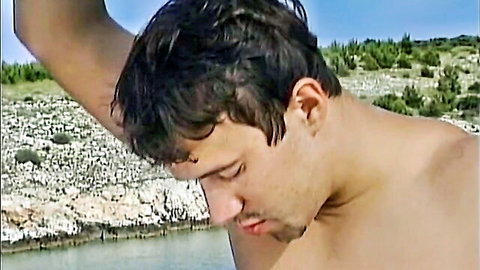 Shirtless man on rocky island beach in Island Love Slaves with Kelly Trump