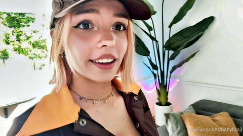 Petite blonde teen in cowboy hat and leather jacket smiles teasingly with cleavage