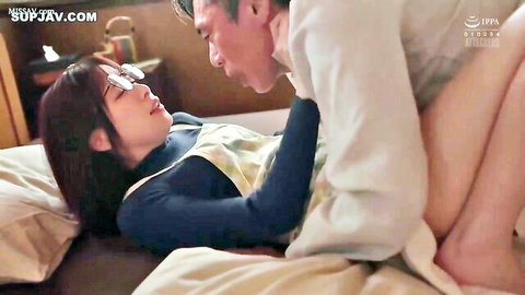 Japanese couple in intimate foreplay on bed, woman with glasses and apron