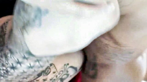 Tattooed arm embracing pale-skinned woman in explicit close-up embrace
