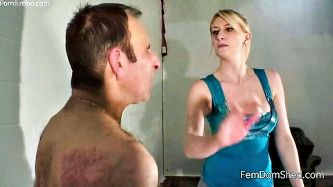 Blonde femdom mistress in tight blue dress slaps shirtless submissive man's face