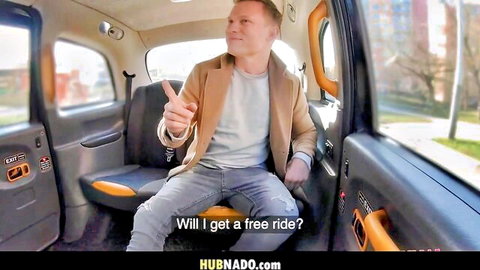 Man in beige jacket sitting in London taxi cab pointing and asking 'Will I get a free ride?'