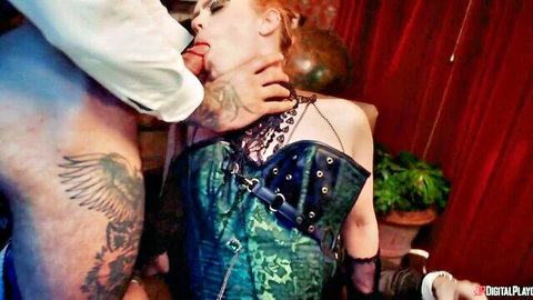 Tattooed man grips redhead's jaw and neck intensely in green fetish corset