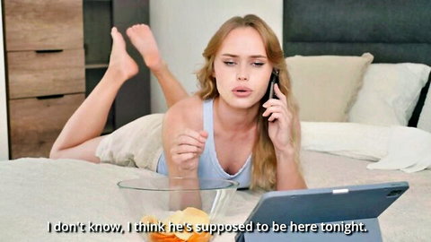 Blonde stepmom in tank top and shorts lounging on bed, talking on phone