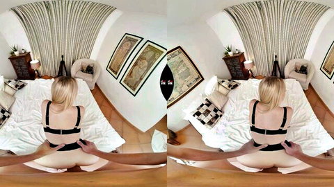 Blonde woman in black bra and white panties posing on bed from behind
