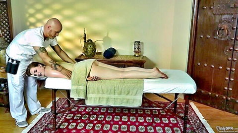 Erotic massage for brunette woman lying nude on table