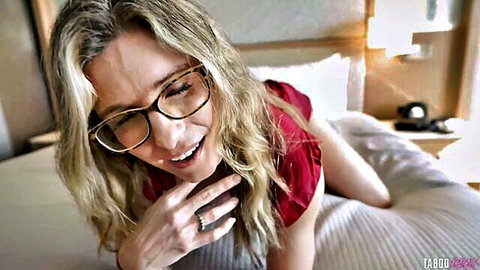 Cory Chase blonde MILF in red top smiling on bed with glasses