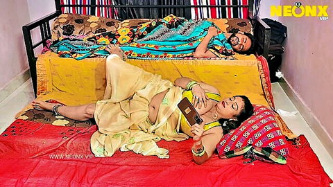 Curvy Indian chachi in yellow saree lying on floor with phone, pregnant belly