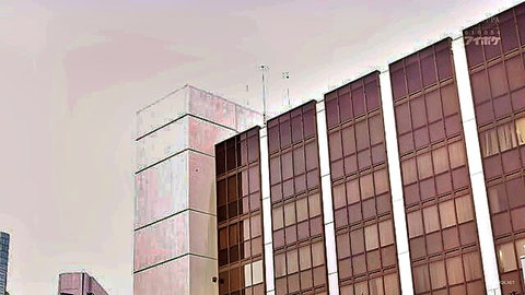 Modern high-rise glass building with reflective windows at dusk under pink sky