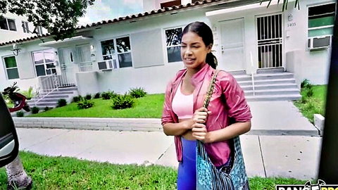 Young Latina teen in pink tank top and leather jacket, standing outside with curvy booty