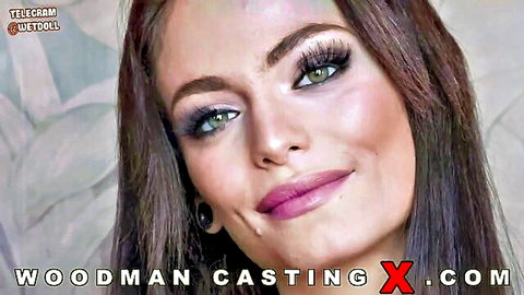 Sexy brunette with green eyes and pink lips smiling seductively in Woodman casting promo
