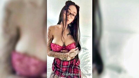 Tattooed Asian babe in pink bra and plaid skirt teasing big tits on bed