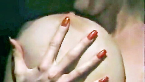 Fair-skinned woman's bronze-nailed hand firmly gripping bald man's shaved head closeup