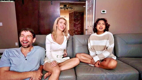 Blonde babe flashing deep cleavage and thighs legs spread next to smiling stepdad and sexy Asian hottie on couch