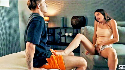 Skinny brunette teen pulls shorts aside fingering wet pussy legs spread over boyfriend on couch