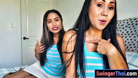Two sexy Thai swingers in striped tops and skirts posing playfully pointing in bedroom