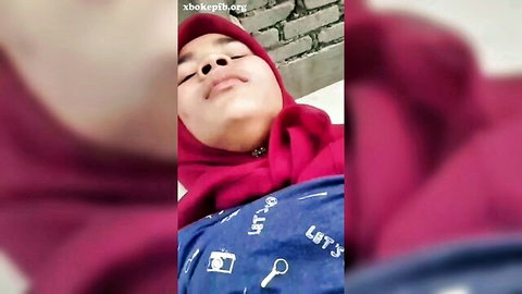 Young Indonesian woman in pink hijab lying down, teasing expression
