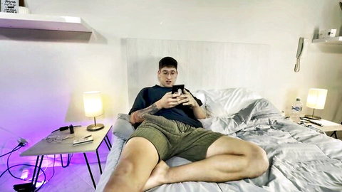 Bastian Blanc lounging on bed in green shorts, muscular legs