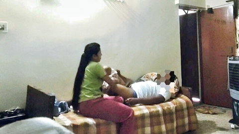 Indian woman in green top pink pants strokes man's hard cock through white underwear on bed