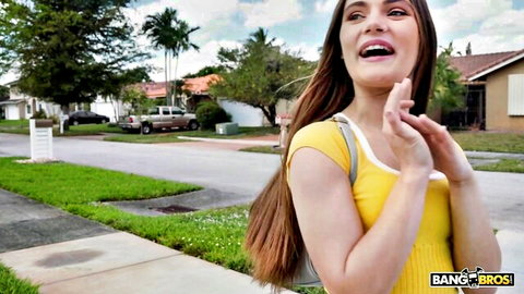 Smiling brunette in tight yellow tank top posing teasingly on suburban sidewalk outdoors Bang Bros