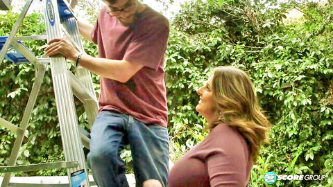 Busty blonde MILF in tight top smiling up at guy on ladder outdoors