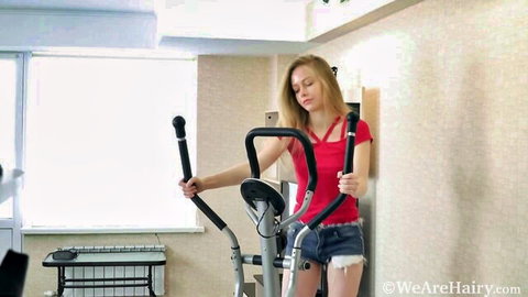 Blonde babe with deep cleavage in tiny frayed denim shorts on elliptical machine