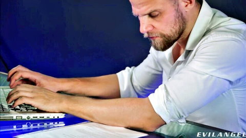 Rocco Siffredi intently typing on laptop in white shirt