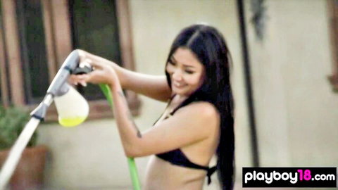 Asian teen babe with small tits in black bikini spraying water hose outdoors sensually