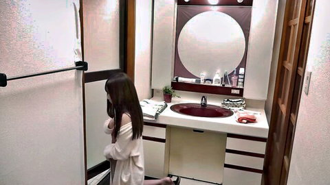 Young Asian wife in white robe kneeling desperately in bathroom
