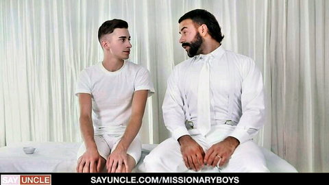 Young twink in white shorts stares at bearded daddy in suit on bed in gay Mormon porn tease