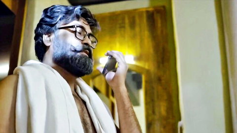 Shirtless bearded Indian DILF in glasses with towel over shoulder holding vape to mouth seductively