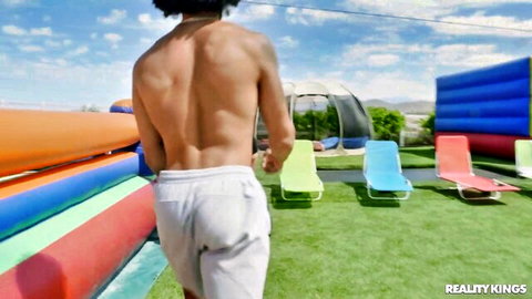 Muscular black hunk in white sweatpants walking outdoors before MMF action