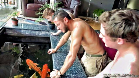 Three shirtless muscular white men leaning over koi pond in Dr. Jezebel scene