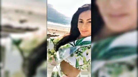 Busty brunette teases deep cleavage in sheer green floral beach dress