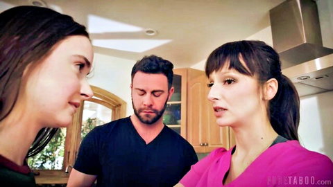 Stepdad in black shirt chats intimately with two brunette stepdaughters in kitchen tops