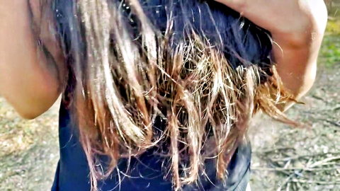 Brunette with long messy wet hair raising arms from behind outdoors in jungle