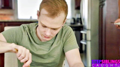 Redhead stepbrother sits at kitchen table with hand near crotch in taboo stepsiblings caught scene