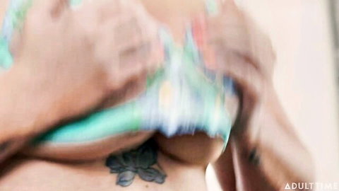 Busty woman pulls down colorful bikini top exposing huge tits and flower tattoo