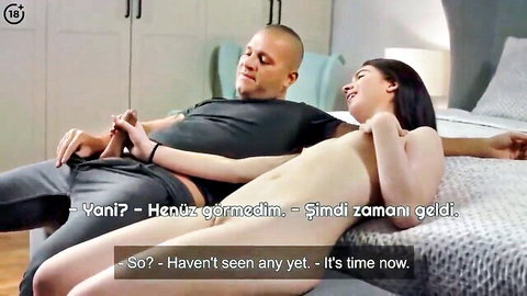 Bald man smiles at nude young brunette lying naked on bed exposing tits and shaved pussy