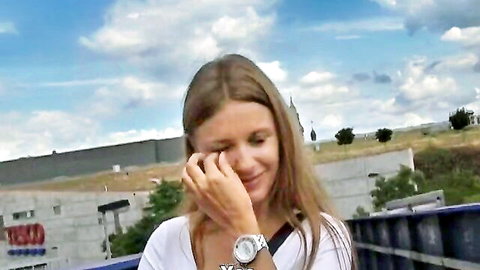 Smiling Caucasian woman with long brown hair in white top, outdoor street pickup tease