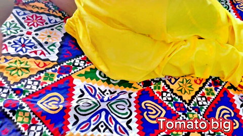 Desi woman in yellow saree draped seductively on patterned rug, big tomato tease