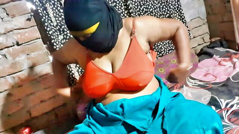 Veiled Muslim woman in orange bra and blue drapes posing seductively