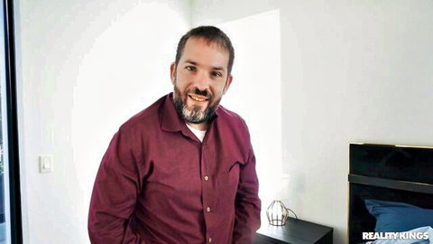 Handsome bearded man in maroon shirt smiling in RK Prime swinger scene