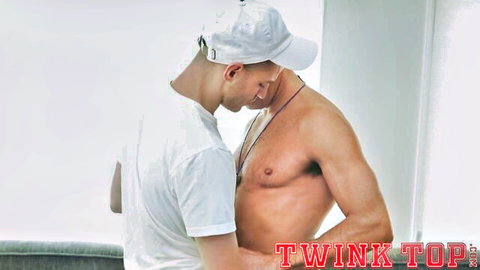 Young athlete in white cap embraces shirtless muscular twink in gay scene