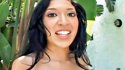 Smiling mixed-race brunette with cleavage in tropical outdoor setting
