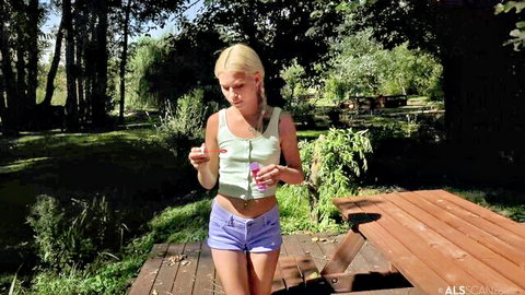 Petite blonde teen with small tits in tight tank top and tiny purple shorts posing outdoors