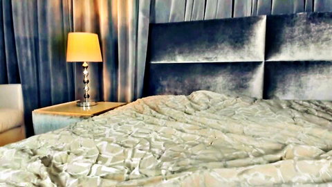 Empty cozy bedroom setup from Chaturbate cam show, dimly lit with beige sheets