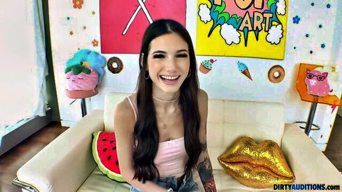 Sophie Tyler smiling in pink top with tattoos, long dark hair