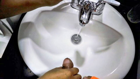 POV of hand stroking hard cock over sink with running water during piss play
